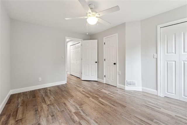 unfurnished bedroom featuring a ceiling fan, light wood-style flooring, visible vents, and baseboards