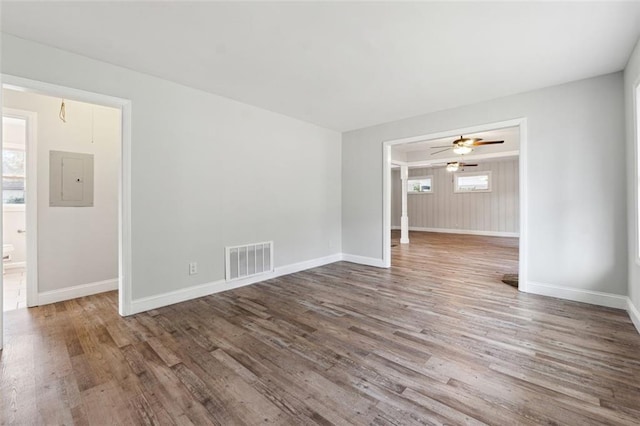 spare room featuring plenty of natural light, wood finished floors, visible vents, and baseboards