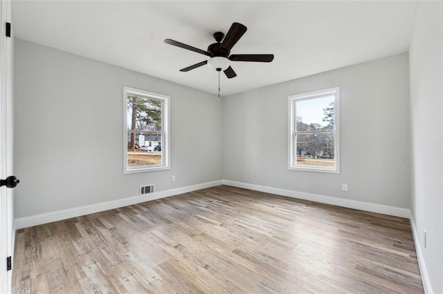 empty room featuring baseboards, a ceiling fan, visible vents, and light wood-style floors