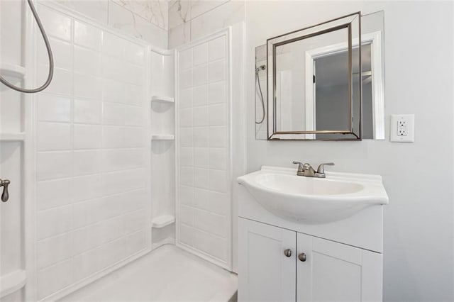 bathroom with tiled shower and vanity