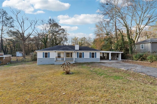 ranch-style house featuring a chimney, covered porch, a front yard, a carport, and driveway