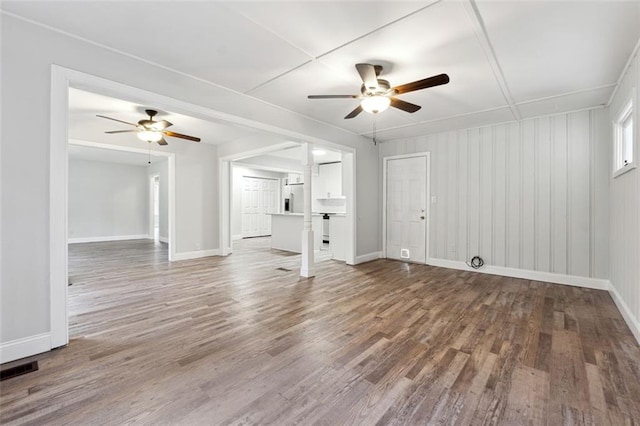 unfurnished living room featuring ceiling fan, wood finished floors, visible vents, and baseboards