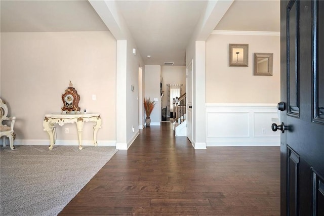 entrance foyer with dark wood-type flooring, wainscoting, a decorative wall, and stairway