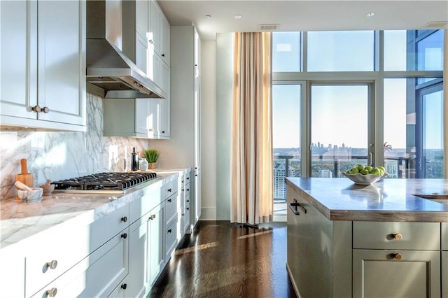 kitchen featuring stainless steel gas cooktop, extractor fan, light stone countertops, decorative backsplash, and white cabinets