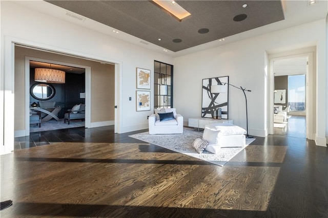 living area with dark hardwood / wood-style floors and a raised ceiling