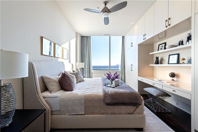 bedroom with a water view, built in desk, and ceiling fan