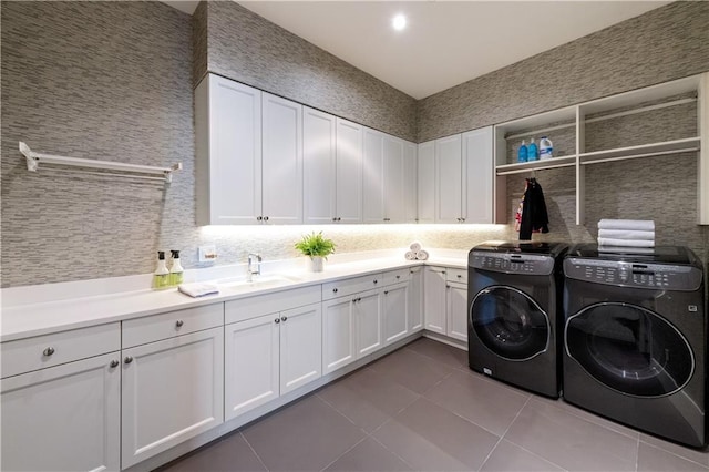 washroom featuring sink, dark tile patterned floors, cabinets, and washing machine and clothes dryer