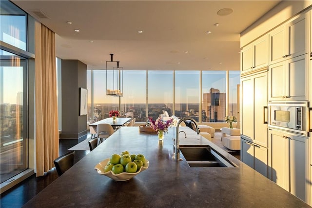 kitchen featuring expansive windows, sink, pendant lighting, and built in appliances