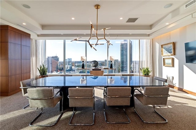 dining area with a tray ceiling, light carpet, a chandelier, and a wall of windows