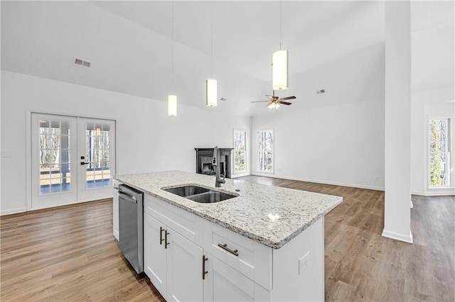 kitchen with light wood-type flooring, dishwasher, a kitchen island with sink, white cabinetry, and ceiling fan