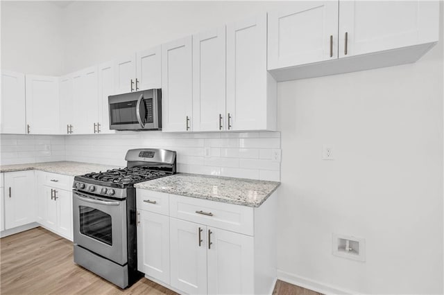 kitchen featuring stainless steel appliances, light wood-type flooring, and white cabinetry