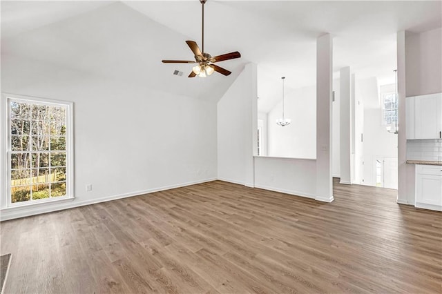 unfurnished living room with hardwood / wood-style floors, ceiling fan, and high vaulted ceiling