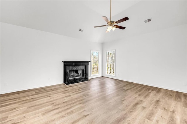 unfurnished living room with light hardwood / wood-style flooring, vaulted ceiling, ceiling fan, and a fireplace