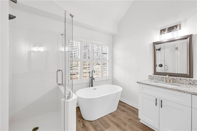 bathroom with wood-type flooring, lofted ceiling, vanity, and plus walk in shower