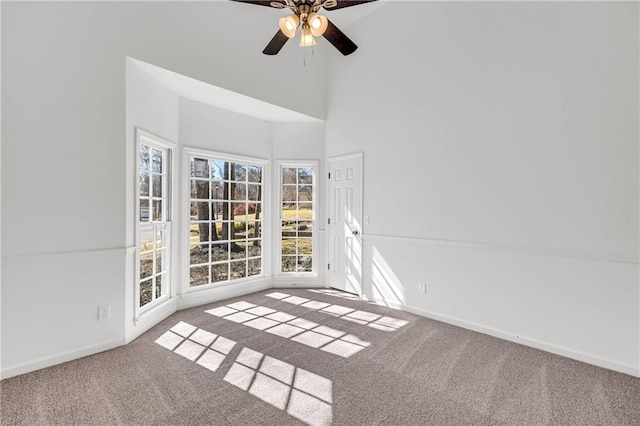 unfurnished room with carpet, a towering ceiling, and ceiling fan