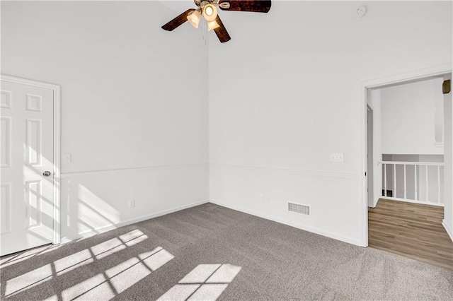 carpeted empty room featuring ceiling fan and a high ceiling