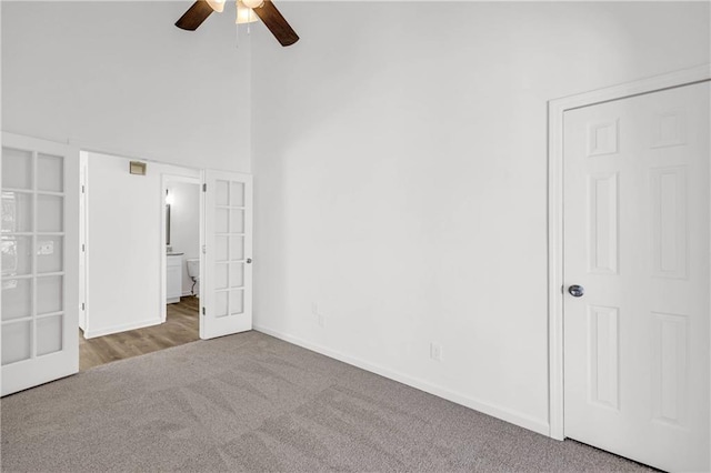 unfurnished bedroom featuring a towering ceiling, ceiling fan, and carpet floors