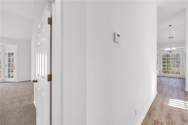 corridor with a notable chandelier and light hardwood / wood-style flooring