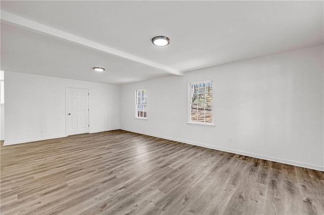 spare room with light hardwood / wood-style floors and beamed ceiling