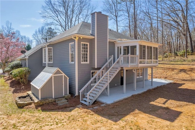 rear view of property featuring a storage shed, a sunroom, and a patio area