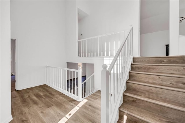 staircase with wood-type flooring and a high ceiling