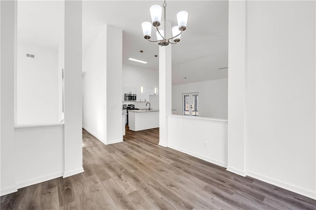 unfurnished dining area with wood-type flooring, sink, and a notable chandelier