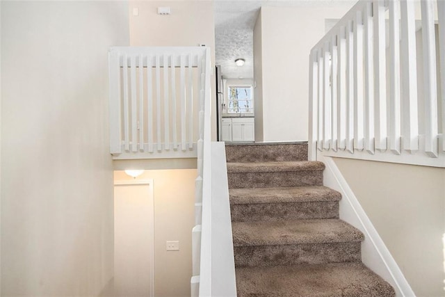 stairway featuring a textured ceiling and radiator heating unit