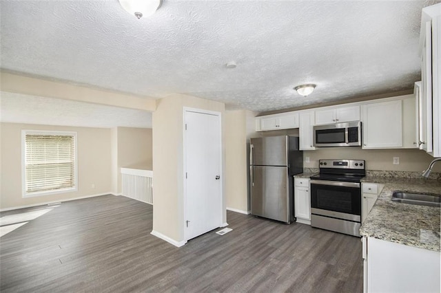 kitchen with sink, dark wood-type flooring, appliances with stainless steel finishes, a textured ceiling, and white cabinets