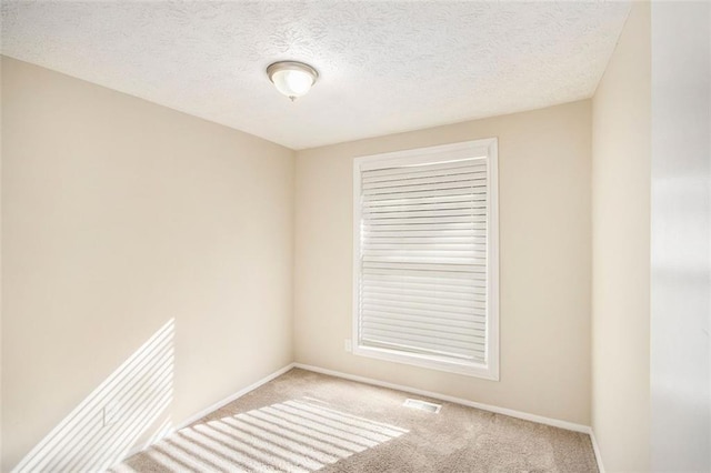 carpeted empty room featuring a textured ceiling