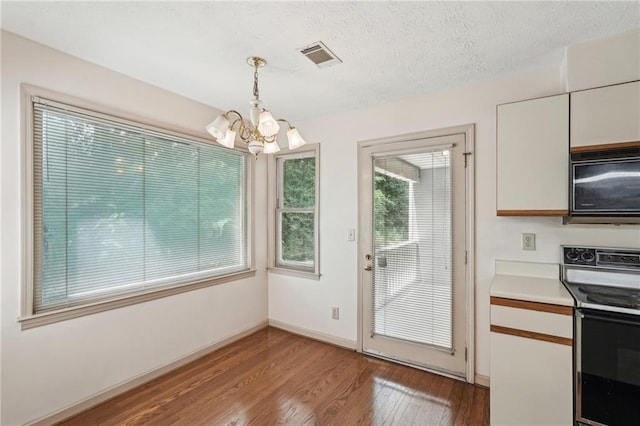 unfurnished dining area with visible vents, light wood-style floors, baseboards, a textured ceiling, and a chandelier
