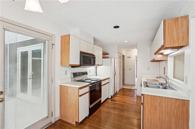 kitchen with a sink, light countertops, black appliances, dark wood-style floors, and white cabinetry