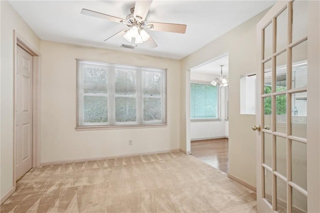 unfurnished bedroom with carpet flooring, baseboards, visible vents, and ceiling fan with notable chandelier