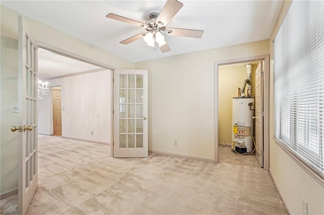 spare room featuring ceiling fan, light colored carpet, french doors, water heater, and baseboards