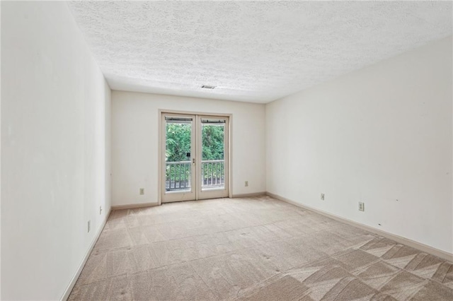 carpeted empty room with french doors, a textured ceiling, baseboards, and visible vents