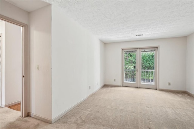 spare room featuring carpet, a textured ceiling, and visible vents