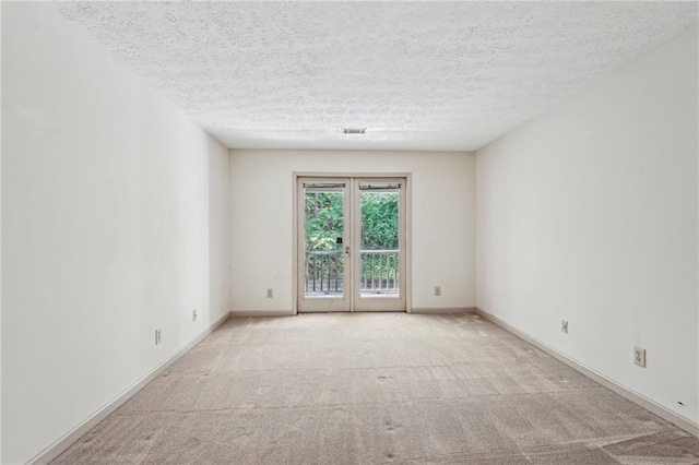 carpeted spare room with visible vents, a textured ceiling, and baseboards