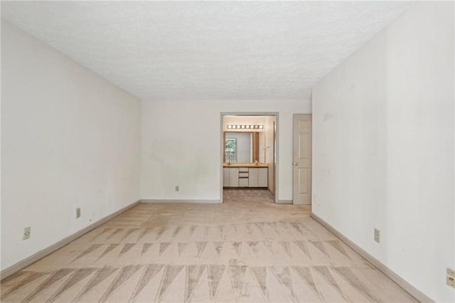 carpeted spare room with baseboards and a textured ceiling