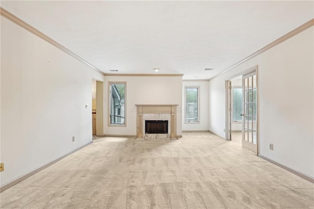 unfurnished living room featuring crown molding, a high end fireplace, plenty of natural light, and light colored carpet