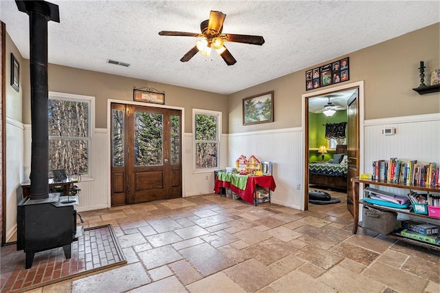 entryway featuring ceiling fan, a wood stove, and a textured ceiling