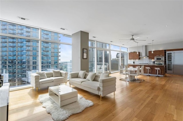 living room featuring floor to ceiling windows, ceiling fan, and light hardwood / wood-style floors