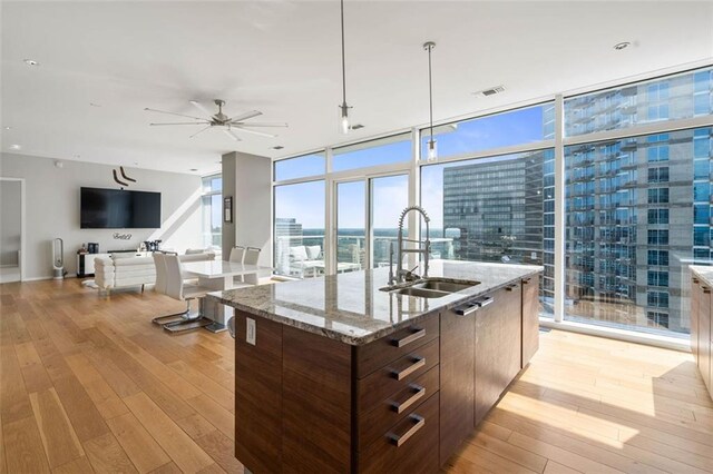 kitchen featuring light hardwood / wood-style flooring, sink, ceiling fan, and a center island with sink