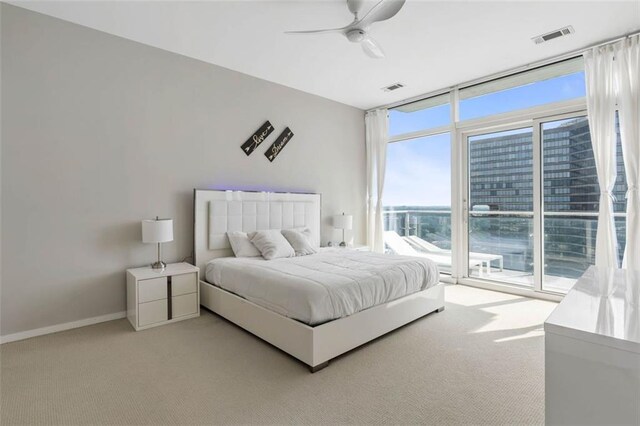 bedroom featuring access to exterior, light colored carpet, ceiling fan, and multiple windows