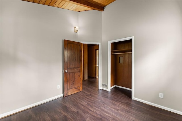 unfurnished bedroom with lofted ceiling with beams, a closet, wood ceiling, and dark wood-type flooring