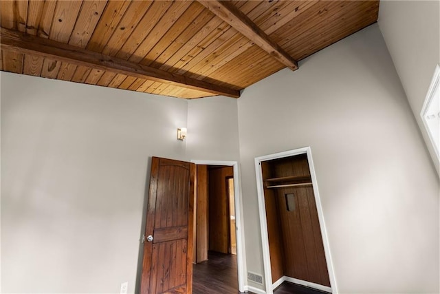 unfurnished room featuring baseboards, dark wood-style floors, vaulted ceiling with beams, and plenty of natural light