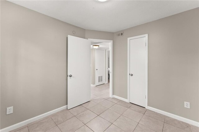 unfurnished room featuring ornamental molding, baseboards, and light tile patterned floors