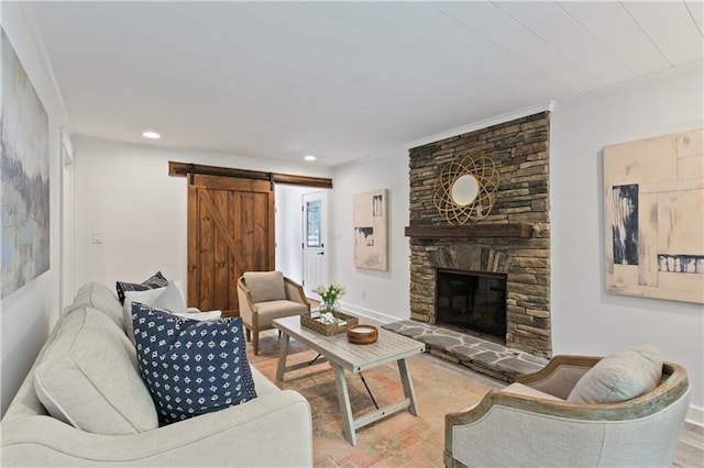 living room with a barn door, hardwood / wood-style floors, and a stone fireplace