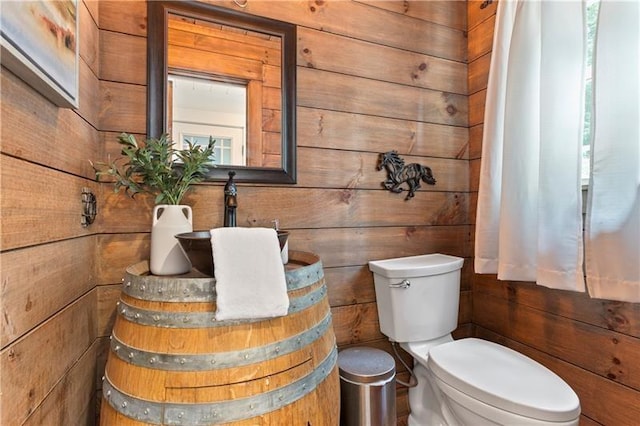 bathroom featuring toilet and wood walls