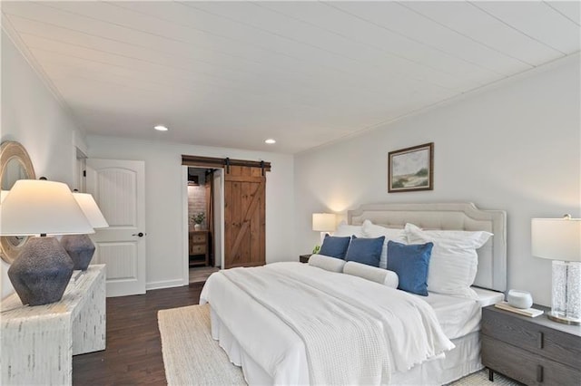 bedroom with a barn door and dark hardwood / wood-style flooring