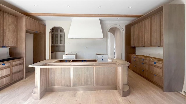 kitchen featuring wall chimney range hood and light hardwood / wood-style floors