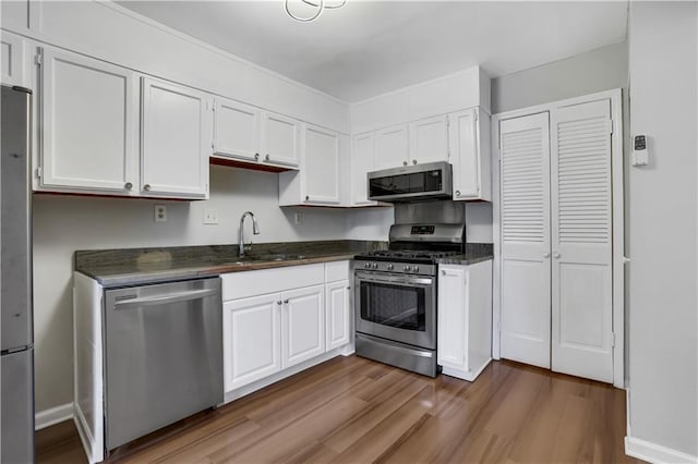 kitchen with sink, hardwood / wood-style flooring, white cabinets, and appliances with stainless steel finishes